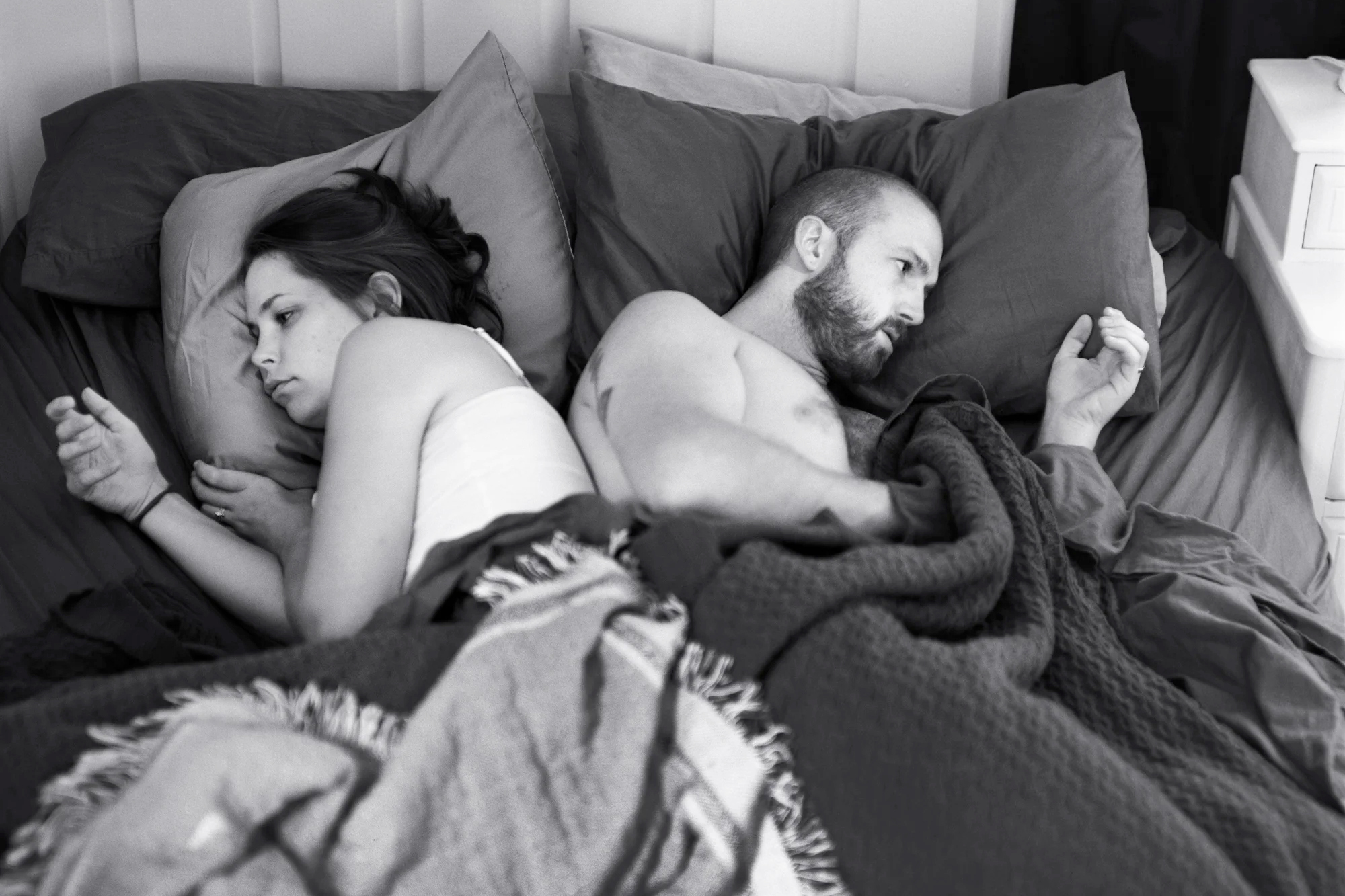 A photo from Eric Pickersgill's 'REMOVED' series – a man and woman in bed stare at their smartphones